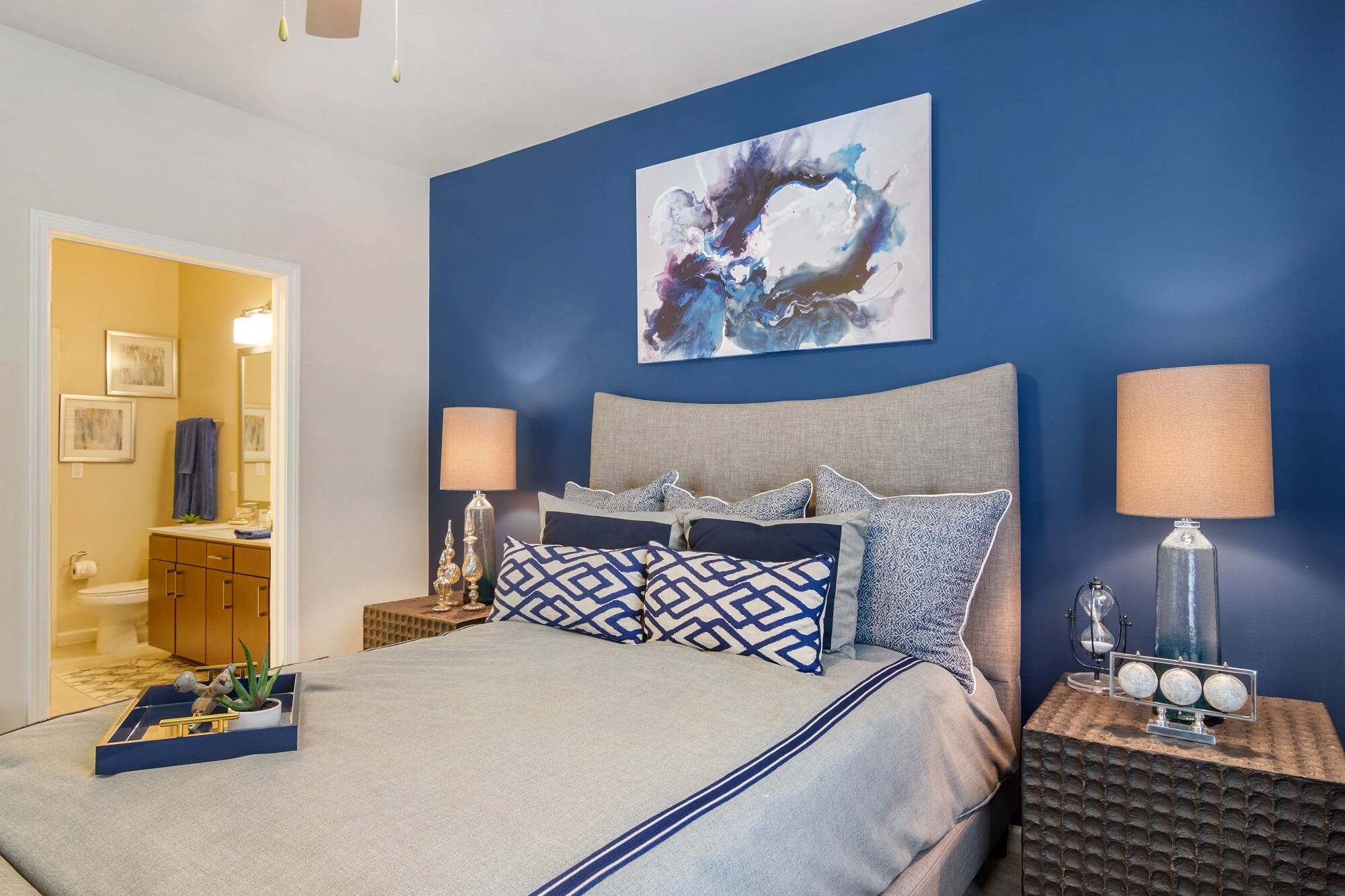 bedroom with accent wall, ceiling fan, and access to the bathroom