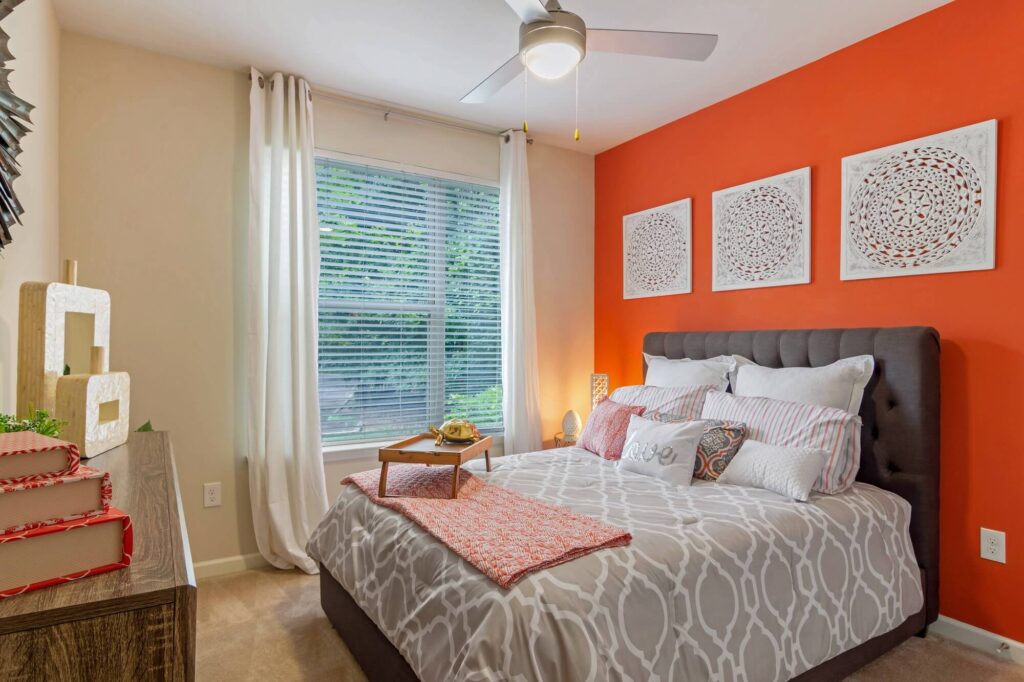 Bedroom with accent wall, carpet floors, ceiling fan, and large window