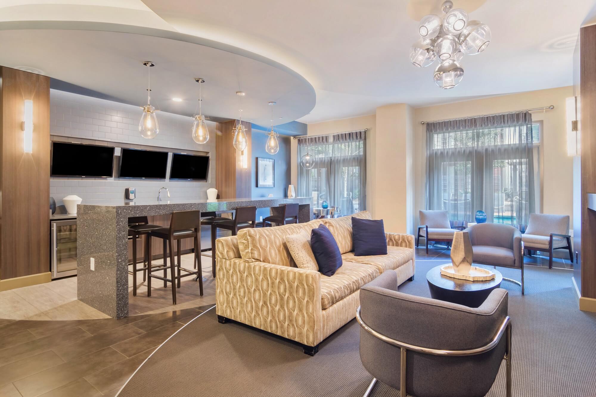 Clubhouse interior with couch and chairs. Kitchen area in the back with sink and tv