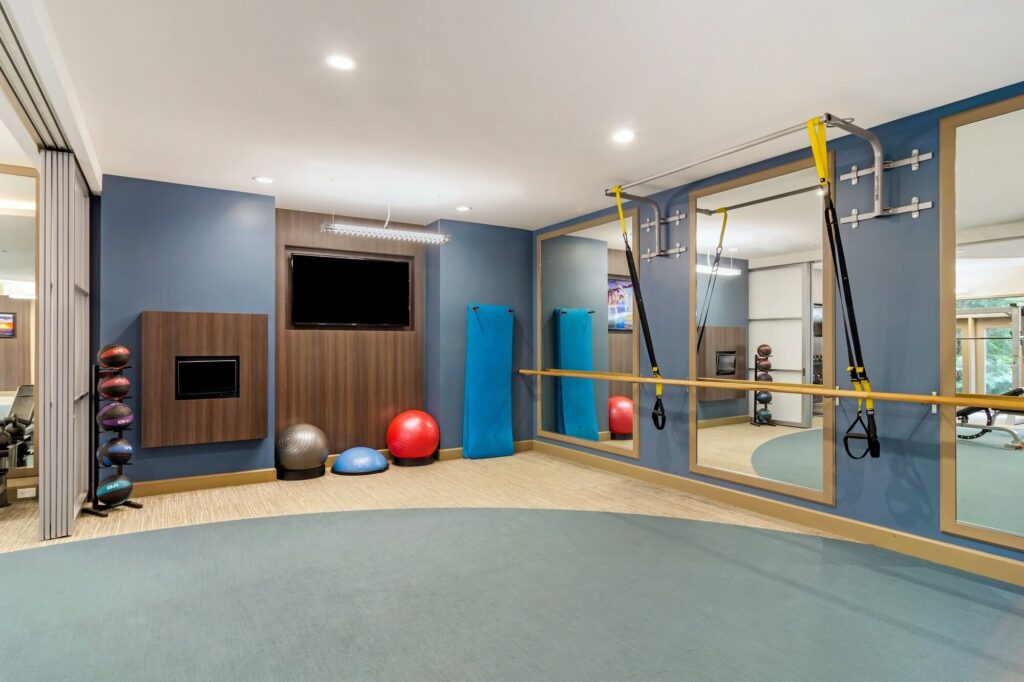 Fitness center with strength training equipment and ballet bar and mirrors