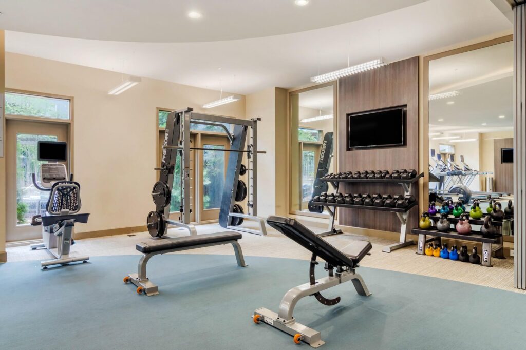 Fitness center with cardio and strength training equipment with free weights and tv mounted on wall