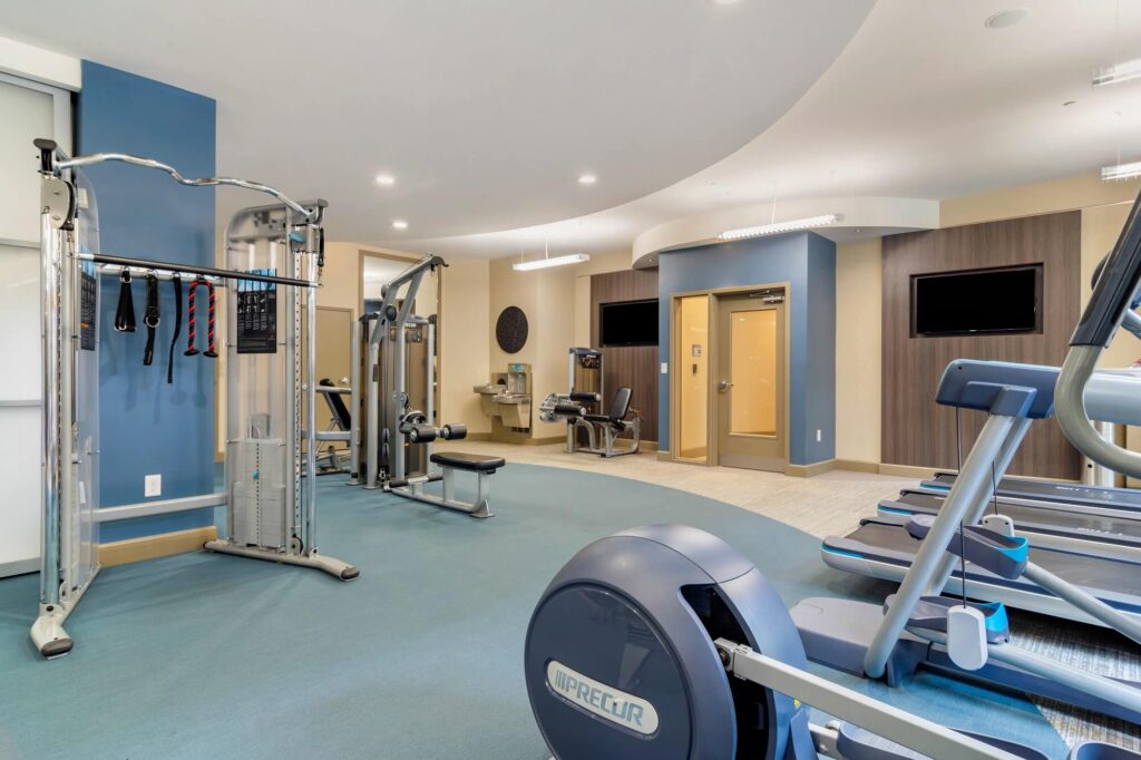 Fitness center with cardio and strength training equipment tvs mounted on the wall