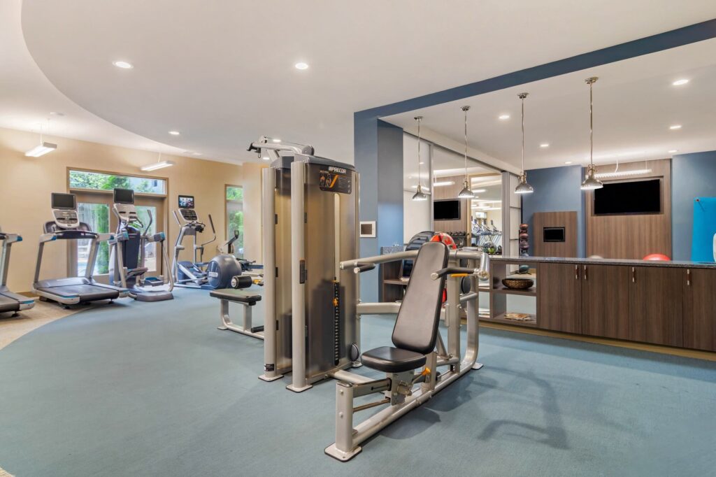 Fitness center with strength training and cardio equipment. Tvs mounted on the wall