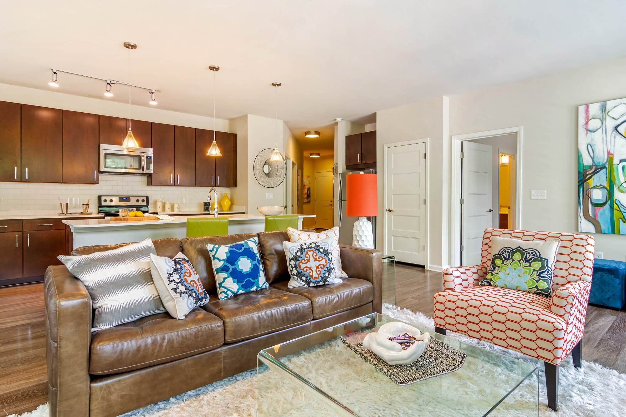 Living room with wood floors with kitchen in the back with stainless steal appliances and wall of windows and access to the bedroom