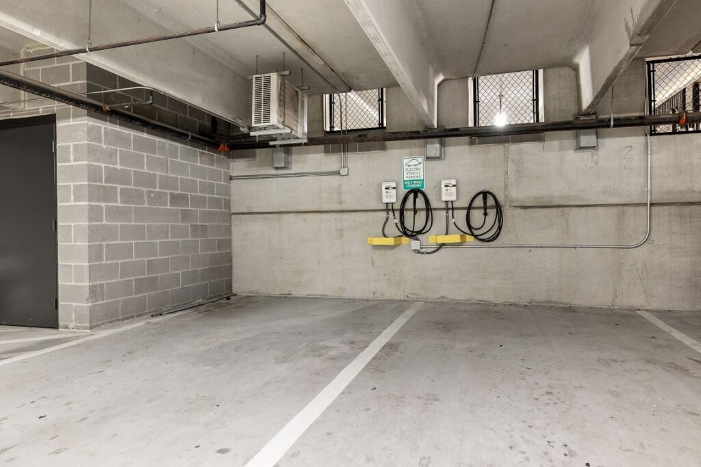Two electric vehicle charging stations mounted on a concrete wall in a parking garage.