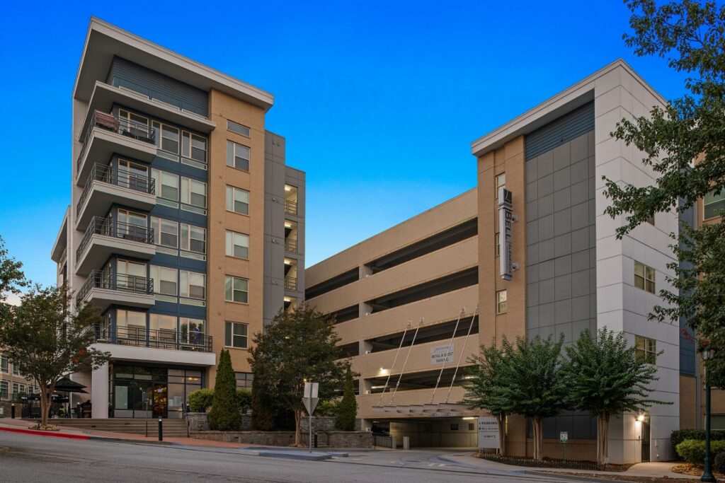 A multi-story residential building connected to a parking garage labeled Bell in the late afternoon.