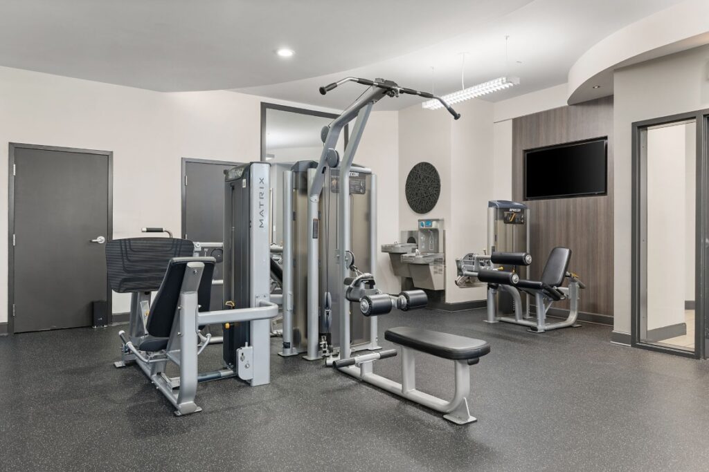 A hotel fitness center with a multi-station weight machine, leg press, and seated leg curl machine.