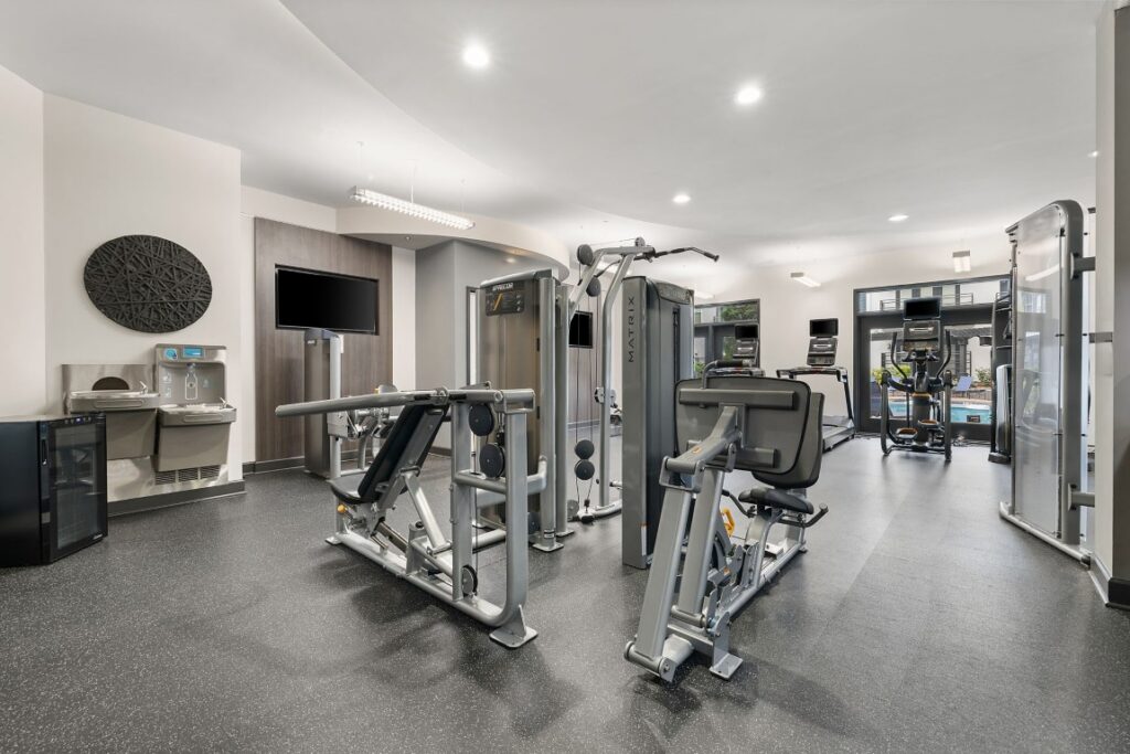Fitness center with multiple strength training machines, a water fountain, and cardio equipment.