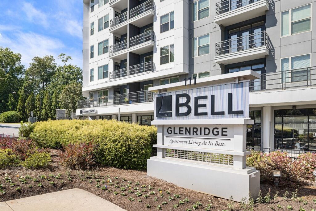 A sign for Bell Glenridge apartment complex in front of a modern multi-story residential building.