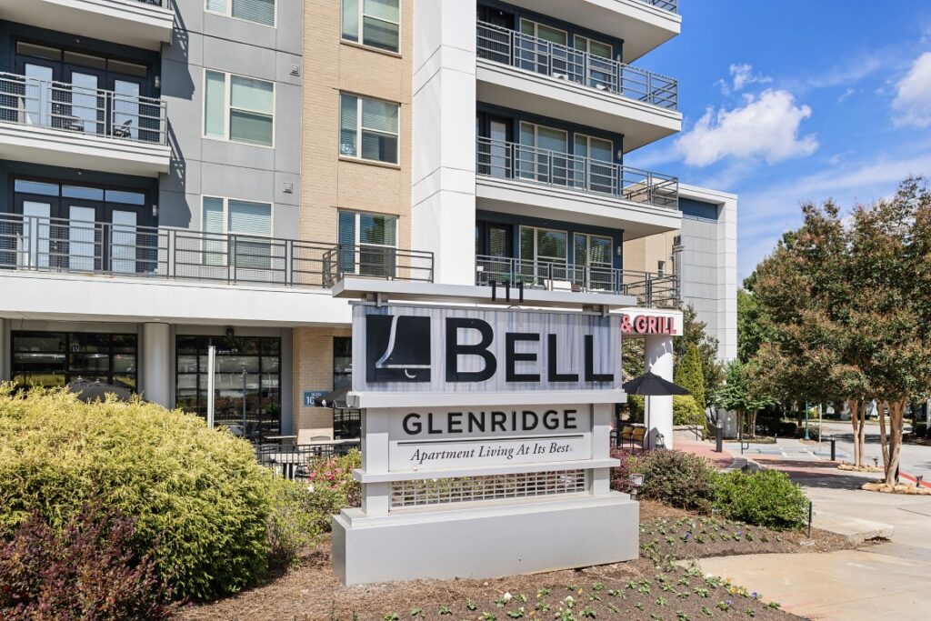 A sign for Bell Glenridge apartment community in front of a modern multi-story apartment building.
