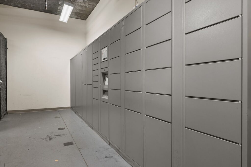 A wall of grey metal storage lockers with a central kiosk for access.